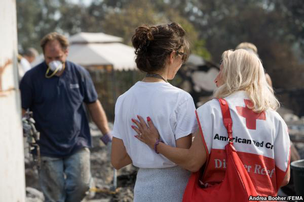 A Red Cross volunteer comforts the sister of fire victim, while friends and volunteers sift through the resident's home searching for valuables.