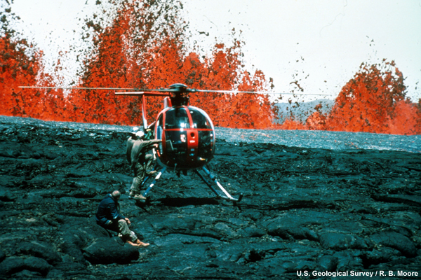 Hawaiian Volcano Observatory geologists at lava fountains. Helicopters provided access to remote areas of the eruption and were essential for safety.  The lava fountain is rising near the helicopter.