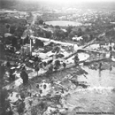 Hilo, Hawaii. Aerial view showing extent of innudation in area of Hilo Electric Company resulting from first wave as secondary wave approaches the area.